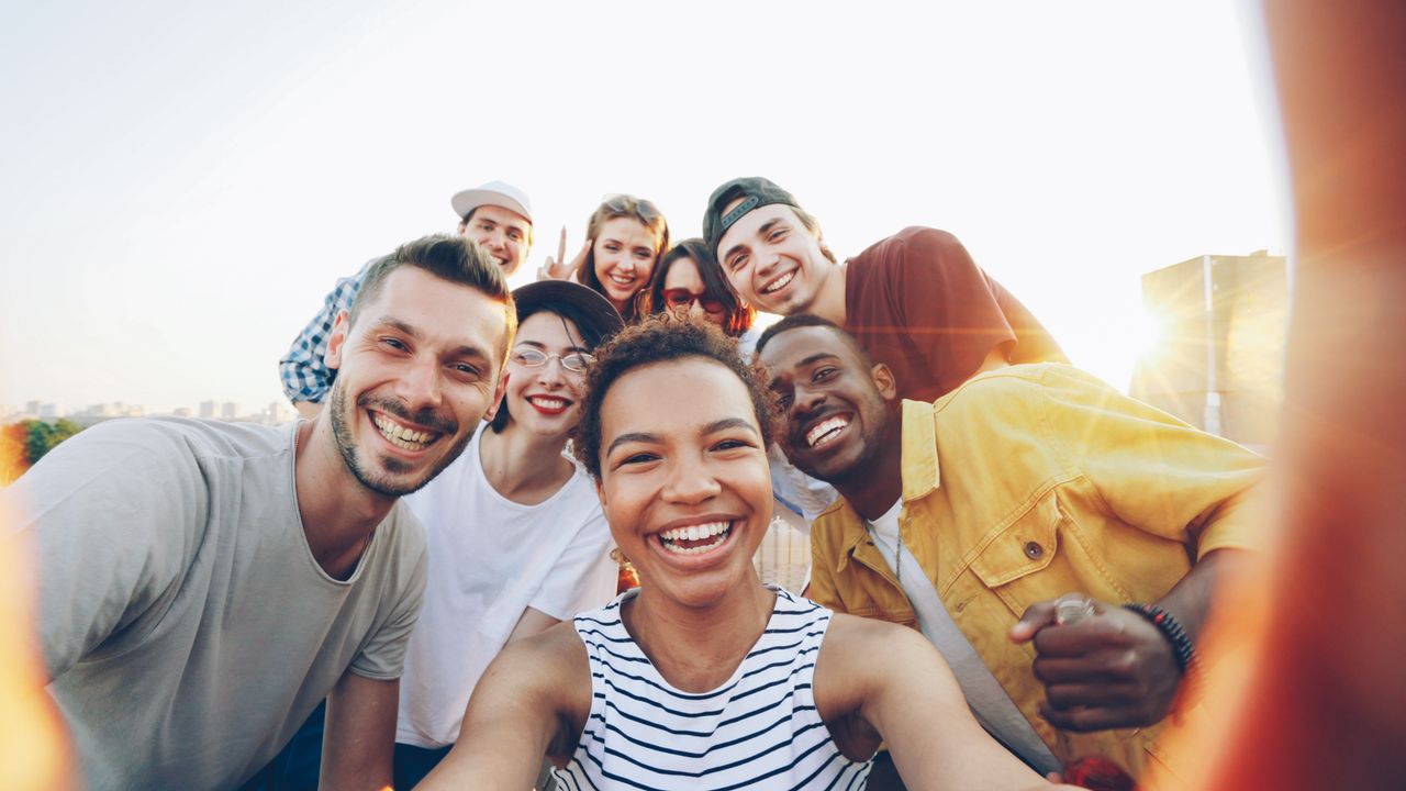 Recursos para diseño estratégico web en empresas 2 A diverse group of friends taking a joyful selfie outdoors during sunset.